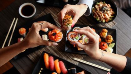 Trois personnes partageant des assiettes de sushis